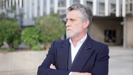 portrait of a mature businessman with crossed arms outdoors