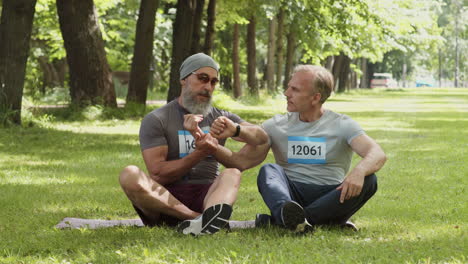 two men relaxing and talking in park after a run