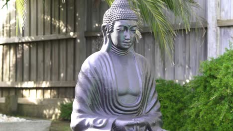 statue of a buddha is abandoned in a backyard and has spiderwebs all over it
