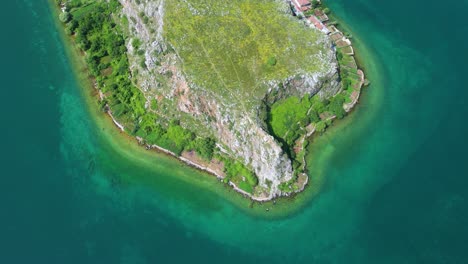 península pedregosa rodeada por las aguas esmeraldas del antiguo lago en el pueblo turístico de lin, pogradec