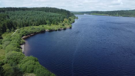 idyllic blue water reservoir lake woodland hiking walk aerial view slow forward push in