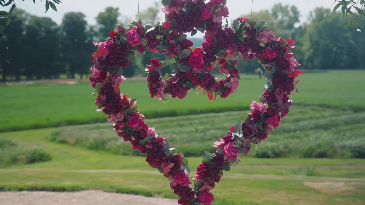 Panoramische opname van hartvormige bloemen voor een bruiloft, met weiden op de achtergrond overdag, buiten, gimbal-opname
