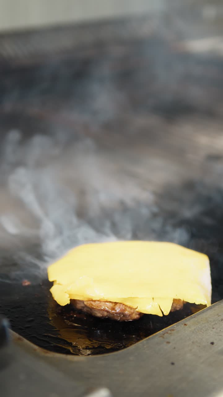 Chef Putting Cheddar On Top Of The Cooking Meat On The Griddle