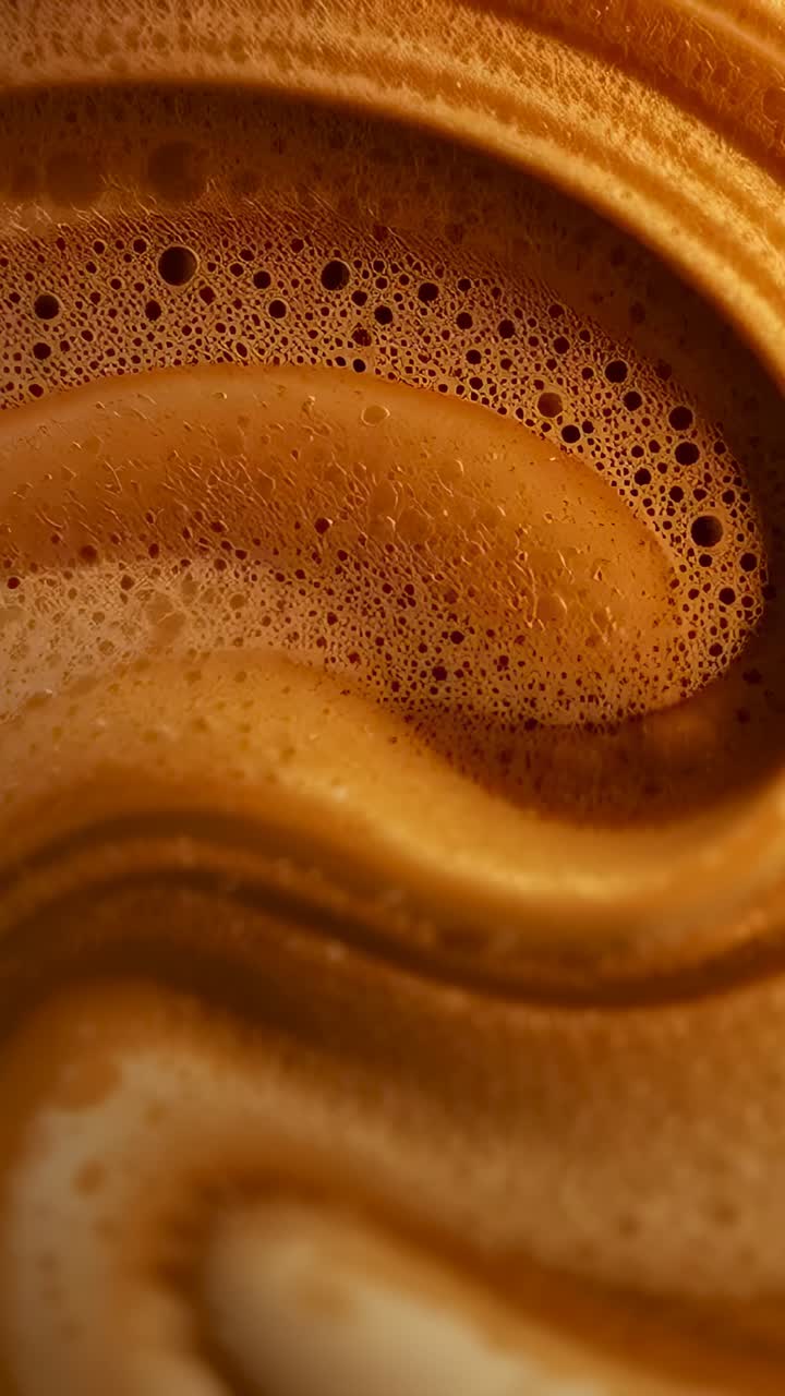 Vertical video: Focusing camera capturing coffee crema shifting in macro cup, with microbubbles