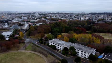 A-cityscape-with-autumn-trees-and-scattered-clouds,-daytime,-aerial-view