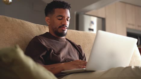 serious ethnic man working on laptop at home