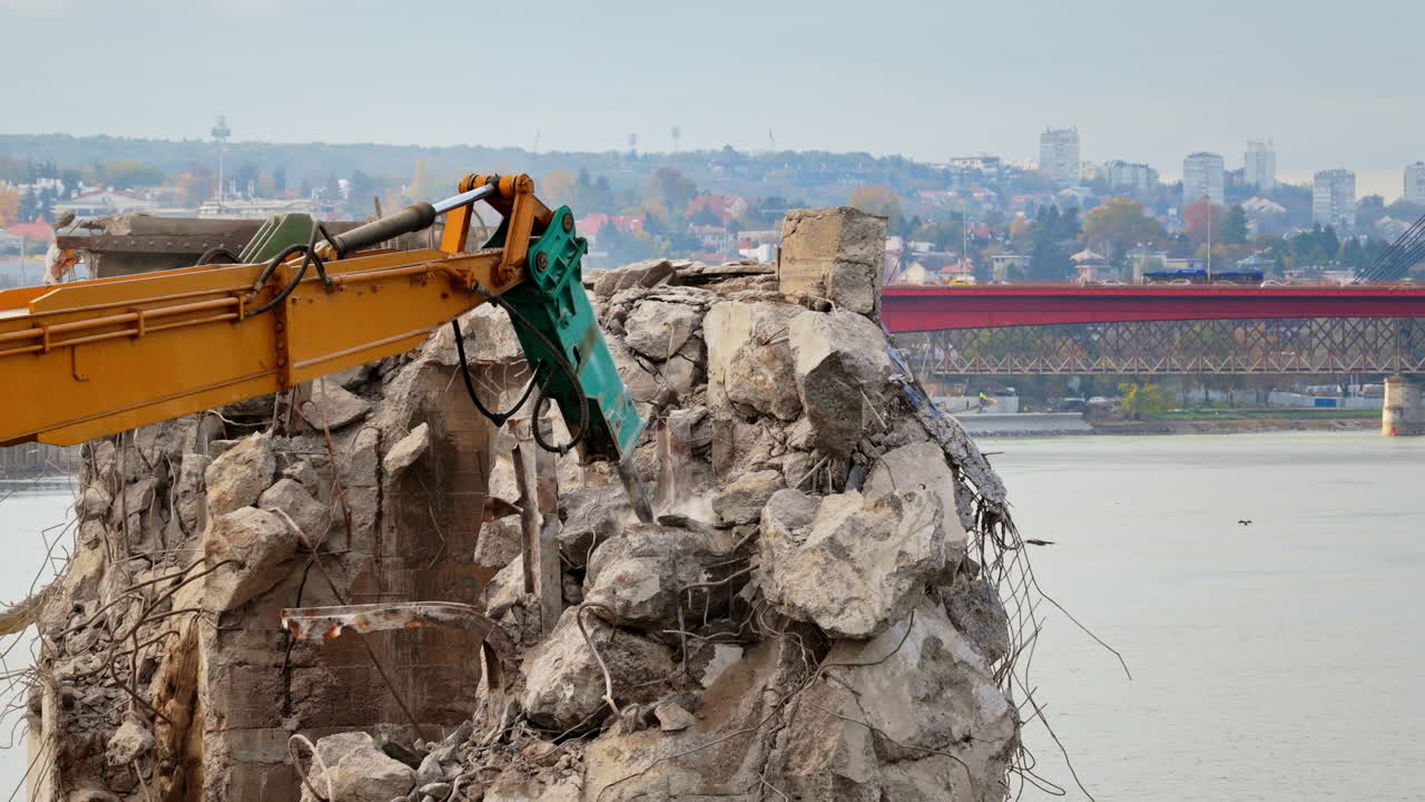 Aerial drone view of heavy demolition machinery crushing concrete on a riverbank construction site in Belgrade, Serbia