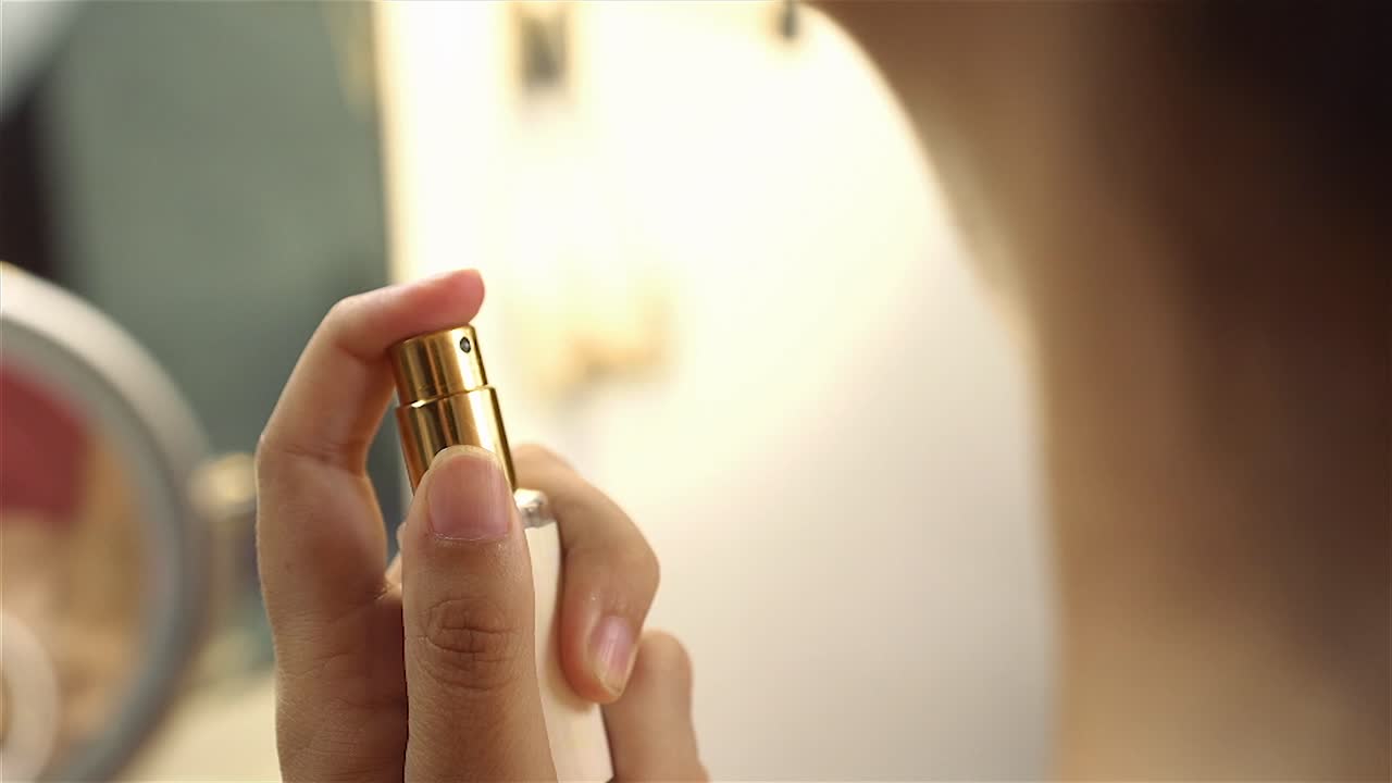 Donna che spruzza profumo sul collo, flacone elegante, primo piano