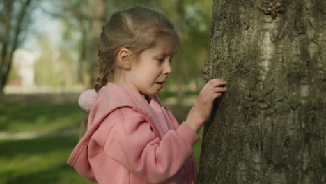 Disgusted-little-girl-looks-at-bugs-on-tree-in-spring-park