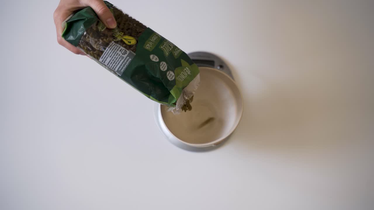 recipiente de llenado a escala digital con pasta verde cruda baja en carbohidratos, sobrecarga