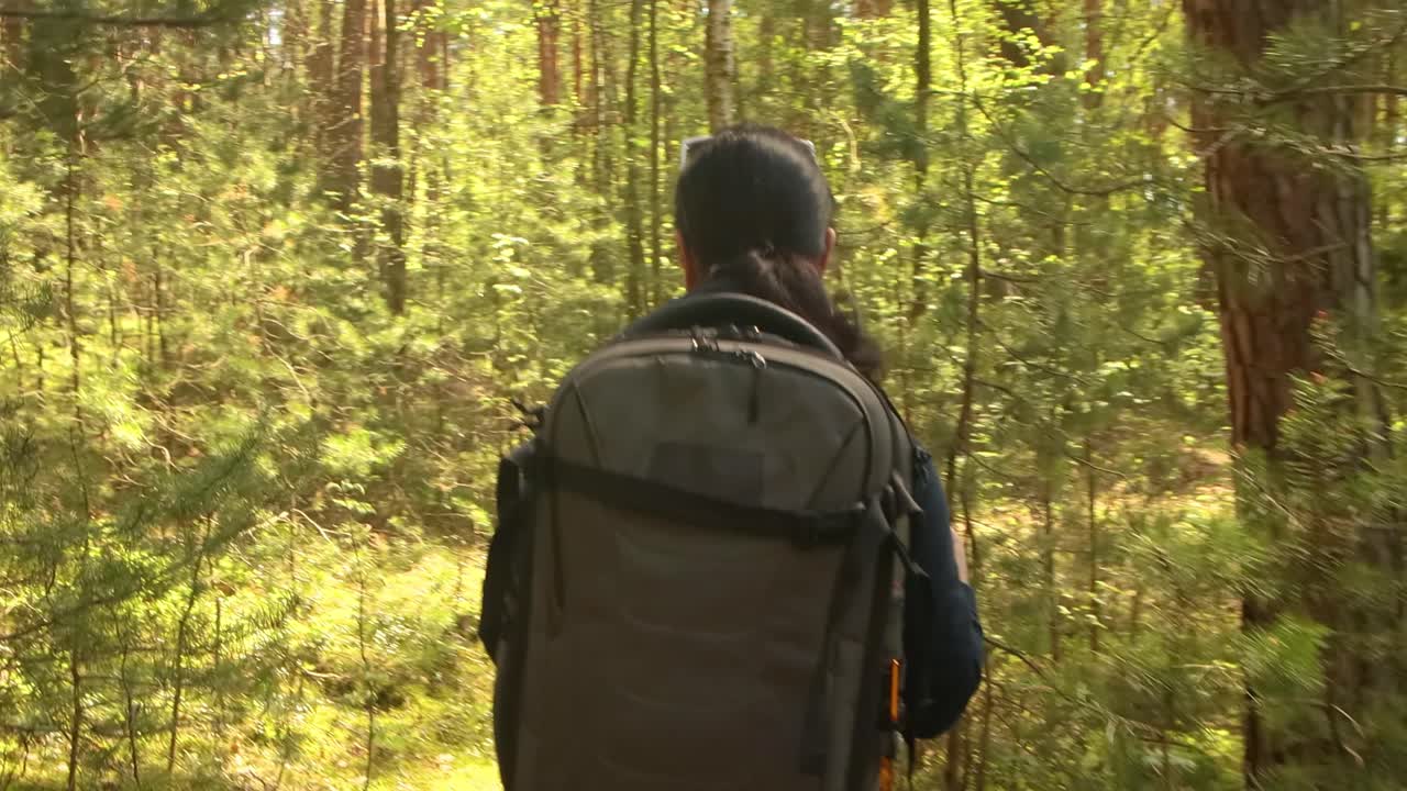 mujer caminando con una mochila de senderismo en el bosque verde de primavera