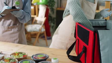 two colleagues packing eco food containers in delivery bag