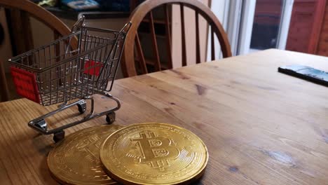Golden-bitcoin-crypto-currency-coins-in-tiny-shopping-trolley-on-kitchen-table-concept-slow-right-rotating-shot