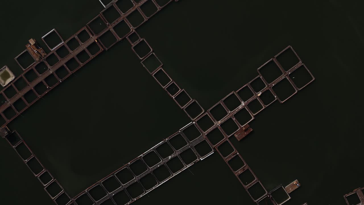 Top-down aerial view of geometric fish farming structures floating in a reservoir