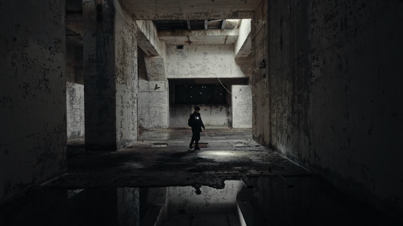 Man with Flashlight Exploring Dark Abandoned Building Interior