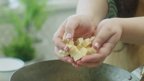 mujer añadiendo cubos de queso en la sartén