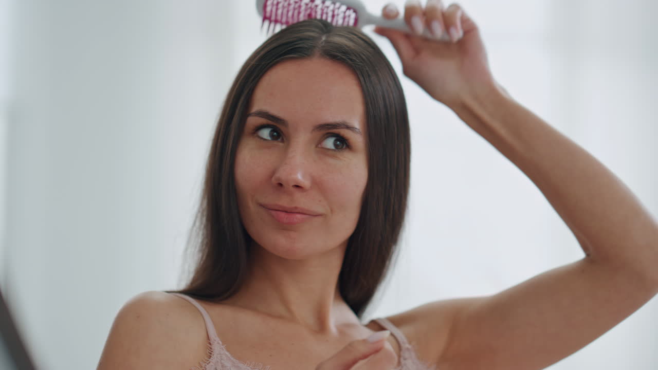 mujer satisfecha cepillando el cabello en el baño de cerca. mujer disfrutando de la rutina de belleza