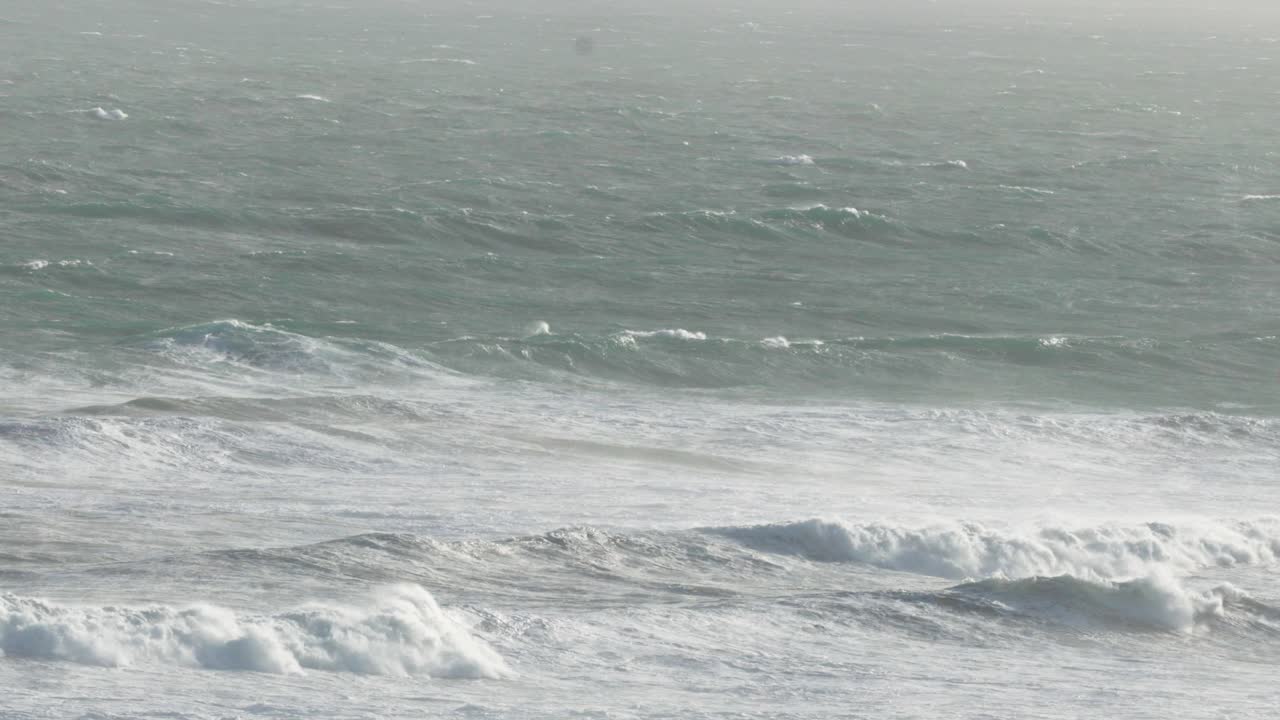 역동적인 바다 파도가 대양 도로를 따라 해안에 부히고, 자연적인 조명과 조용한 분위기로 포착됩니다.