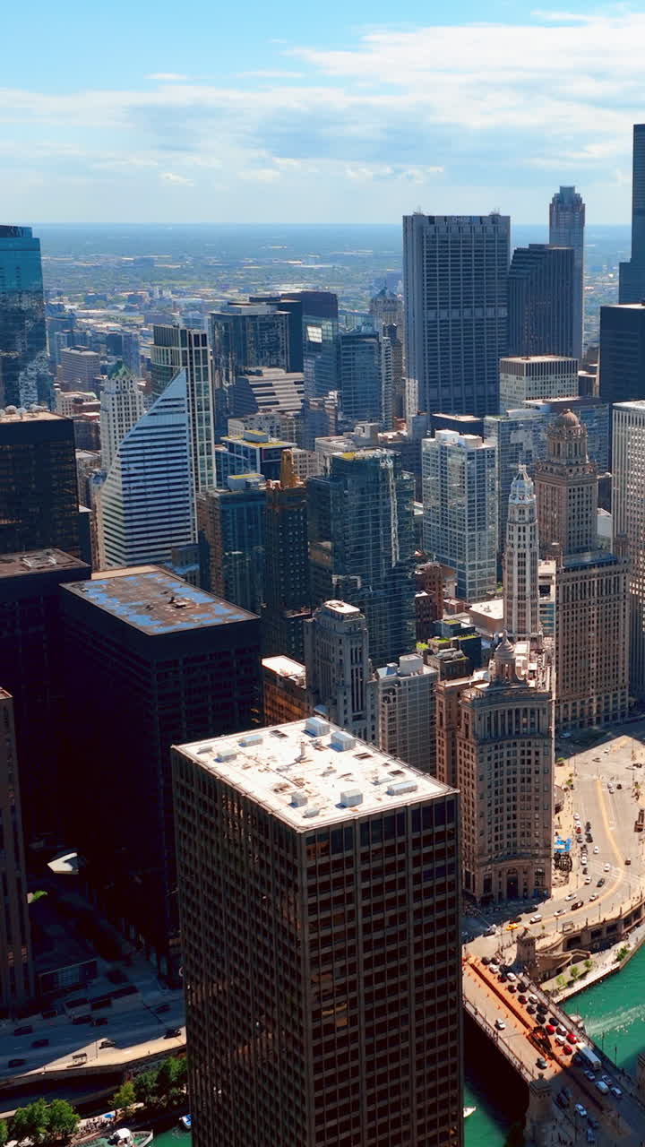 Sorvolo aereo con drone di condomini lungo il fiume Chicago e grattacieli. Edificio commerciale equo nel centro. Ponte sul fiume. Video verticale