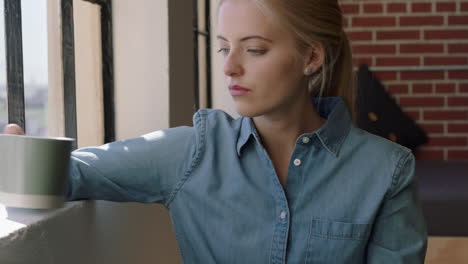 beautiful young woman drinking coffee at home enjoying relaxed morning looking out window thinking planning ahead contemplative