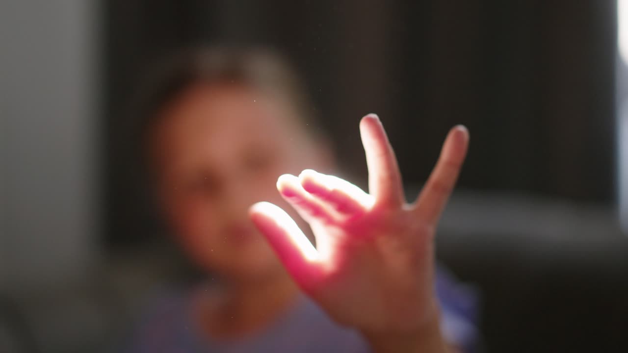 Young Girl Playing with Sunlight Shining Through Her Fingers