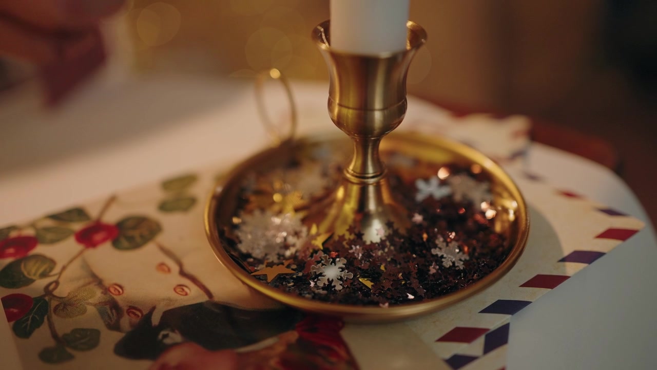 Festive gold candlestick with decorative snowflakes and a Christmas postcard nearby