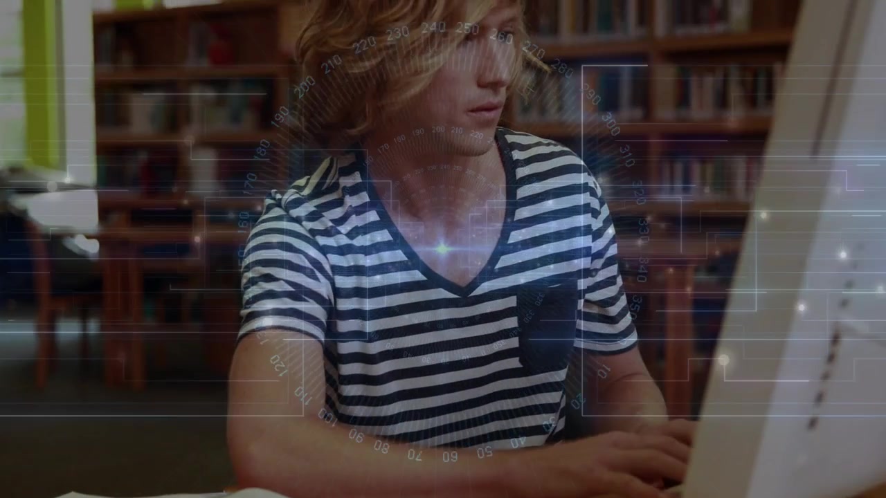 Male student typing on keyboard in study area, activating HUD overlay while referencing textbook