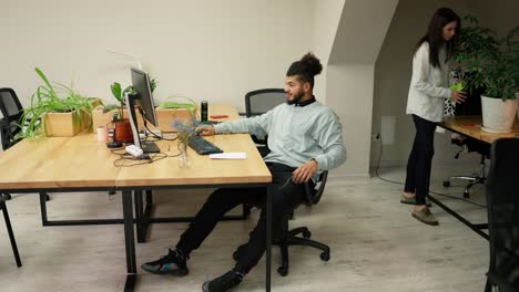 Young-businessman-working-calmly-on-laptop-in-office-with-coworkers-around