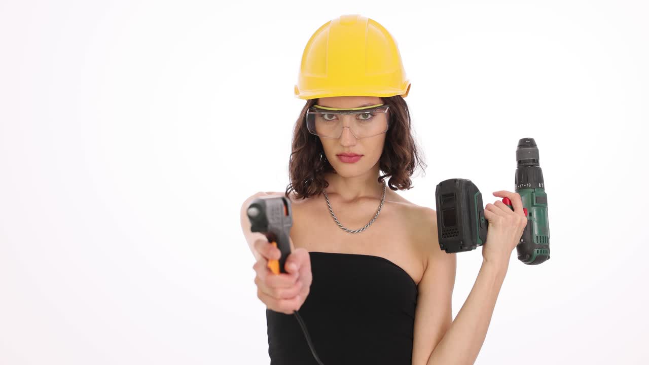 Woman in Hard Hat and Safety Glasses Holding a Glue Gun and Power Drill