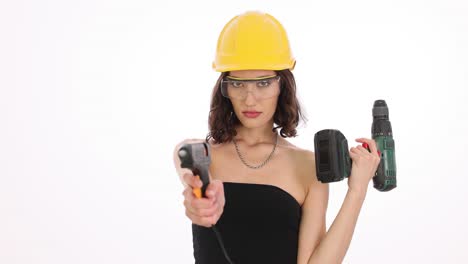 woman in hard hat and safety glasses holding a glue gun and power drill