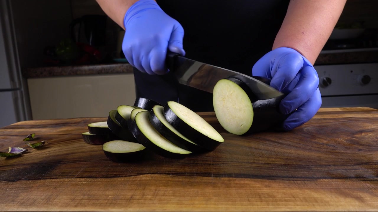Kocken skär en aubergine på en skärbräda