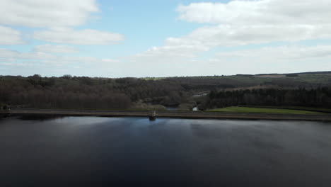 aerial flyover from fewston to swinsty reservoir with car crossing dam inbetween