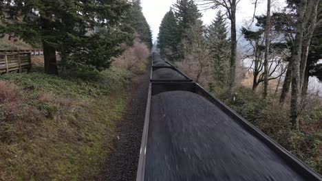 aerial close up of a coal train moving along a train track with a pan down