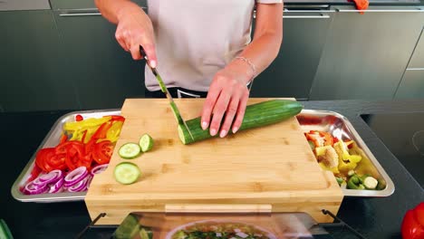 eye perspective on a cutting board with knife and sliced cucumber with other vegetables and tablet with recipe