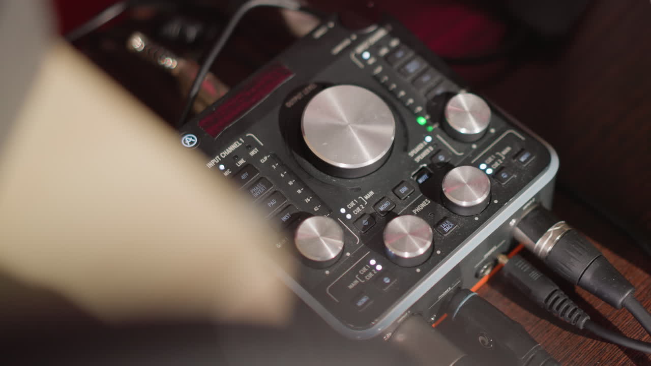 Close-up shot of a sound mixer on a table in a recording studio, featuring various knobs and dials for controlling audio levels