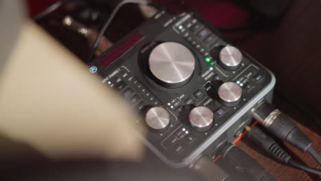 close-up shot of a sound mixer on a table in a recording studio, featuring various knobs and dials for controlling audio levels