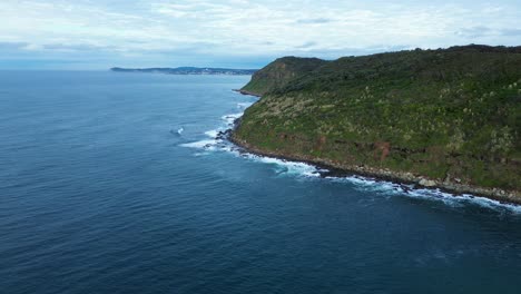 Landscape-drone-aerial-pan-around-rocky-headland-bushland-coastline-Pacific-Ocean-of-Bateau-Bay-Central-Coast-tourism-travel-Australia-nature