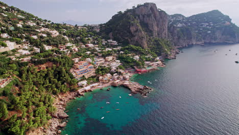 A-dynamic-aerial-shot-approaching-the-beautiful-beaches-and-rocky-cliffs-of-Marina-Piccola-on-Capri,-a-famous-island-that-is-a-popular-luxury-vacation-destination-in-Italy-along-the-Amalfi-Coast