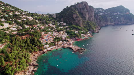 una toma aérea dinámica que se acerca a las hermosas playas y acantilados rocosos de marina piccola en capri, una isla famosa que es un popular destino de vacaciones de lujo en italia a lo largo de la costa de amalfi