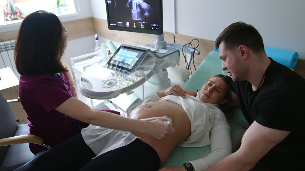 Pregnant woman undergoing ultrasound scan with partner