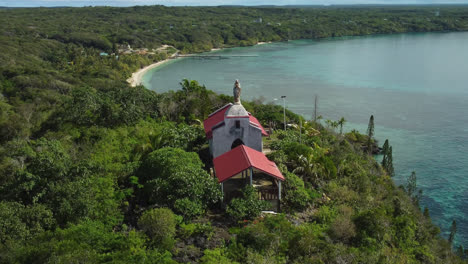 Vista-Aérea-Alrededor-De-La-Capilla-De-Notre-Dame-De-Lourdes,-En-La-Soleada-Isla-De-Lifou,-En-Nueva-Caledonia---órbita,-Disparo-De-Drones