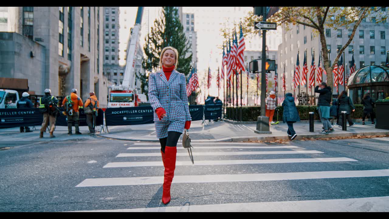 New York, USA, 9 October 2025: Full length of woman in red boots crossing NYC street. Fashionable woman in plaid suit and red high boots walking on crosswalk at rockefeller center