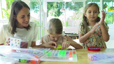 mother and daughters beading together