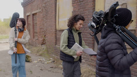 close up view of four coworkers holding material for a recording as they enter a ruined building