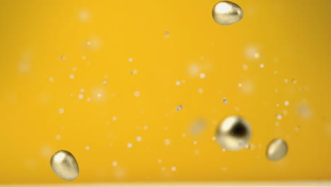 animation of four chocolate golden easter eggs falling and confetti flying on yellow background