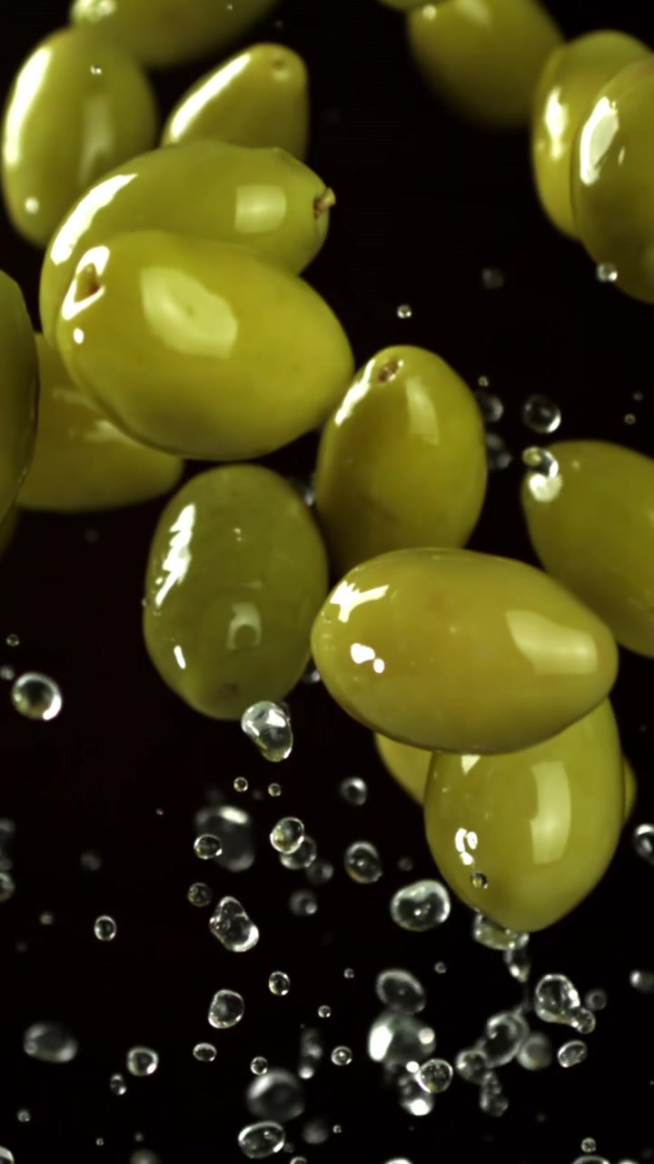 Super rallentatore di olive verdi che cadono con schizzi d'acqua