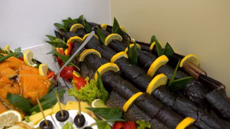 platter with large pieces of smoked fish, adorned with slices of lemon and orange