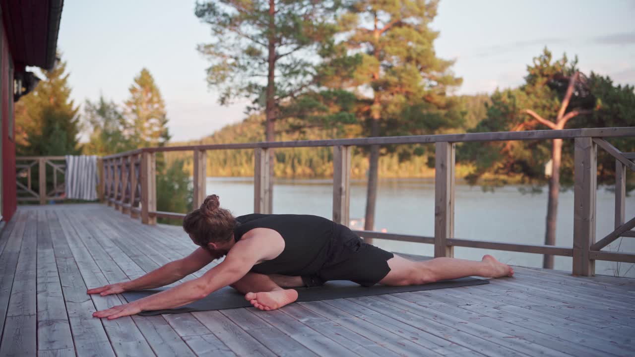 hombre caucásico estirándose en una alfombra de yoga con vista al lago en noruega
