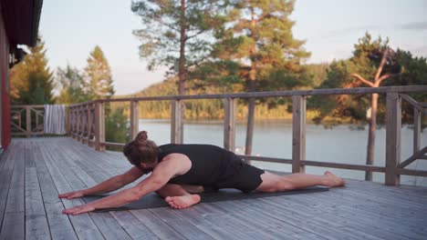 caucasian man stretching on yoga mat with view of the lake in norway