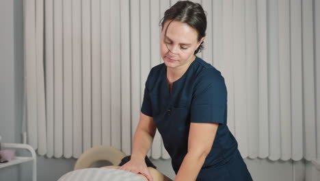 wellness technician massaging side ribs of spa guest on massage bed under bright ring light in modern room with skincare tools visible creating relaxing therapeutic atmosphere for client comfort